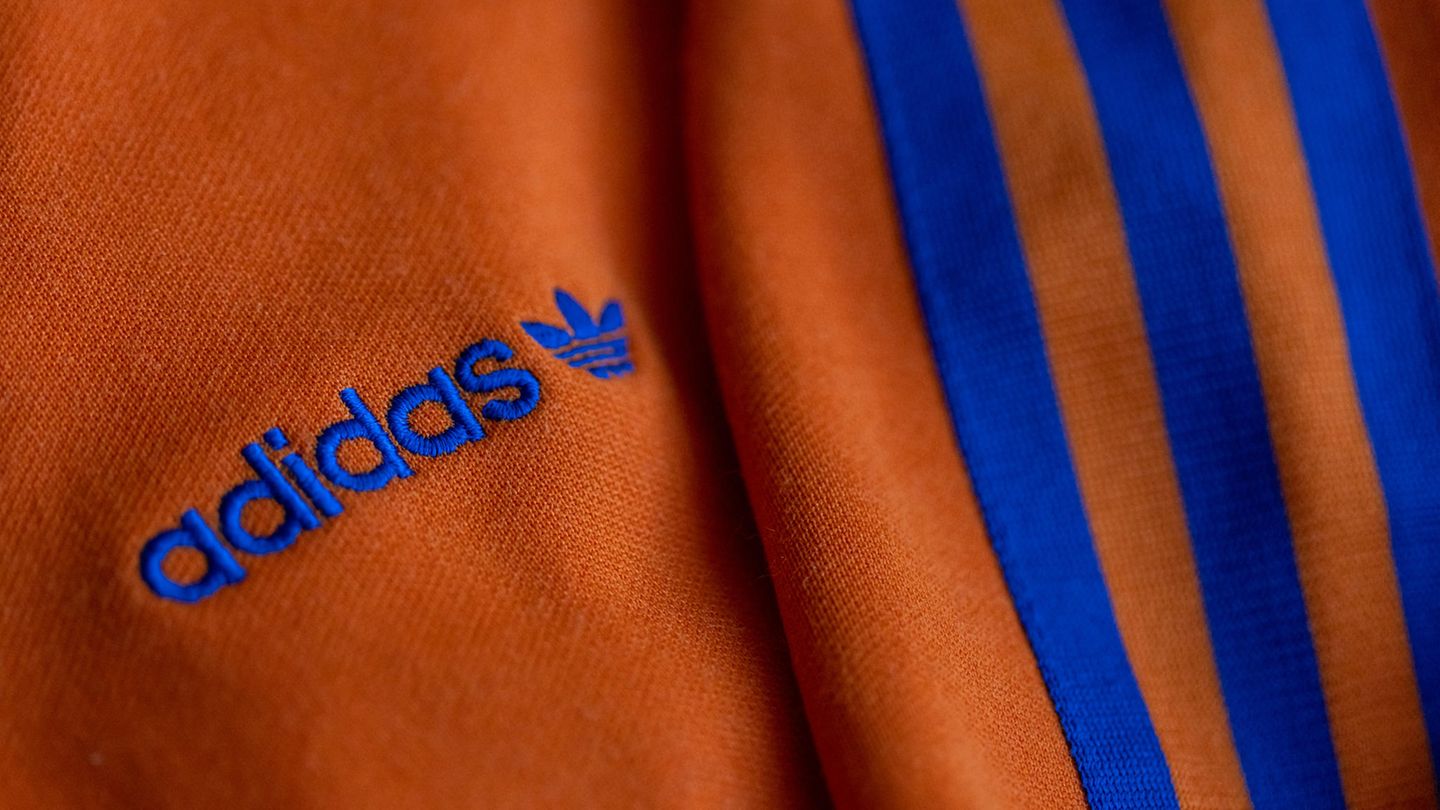 Das Logo des Sportartikelherstellers adidas in Blau auf einer orangefarbenen Jacke