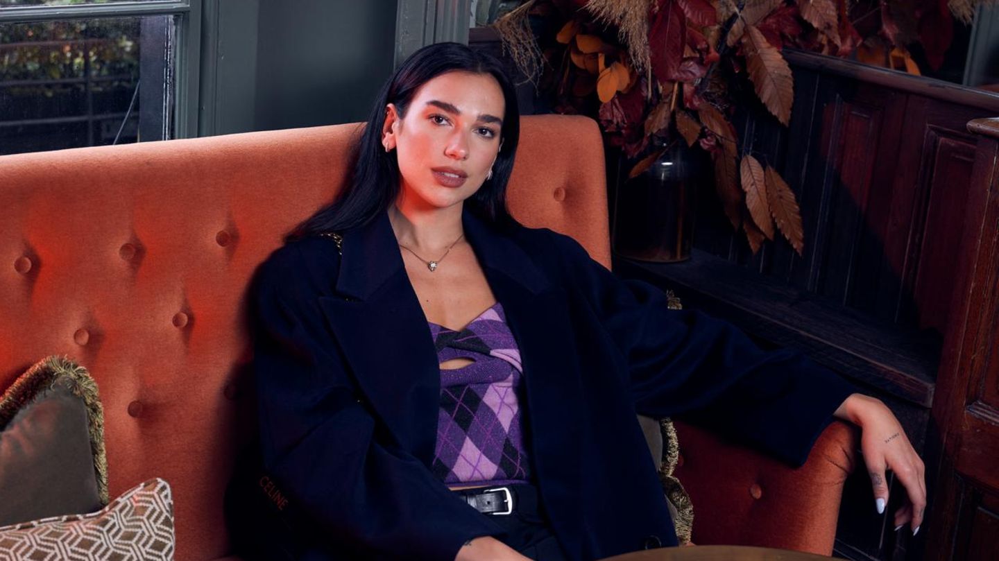 Dua Lipa schaut auf der Couch in die Kamera