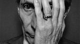 Charlie Watts im Schwarzweiß Portrait mit einer Hand vor dem Gesicht