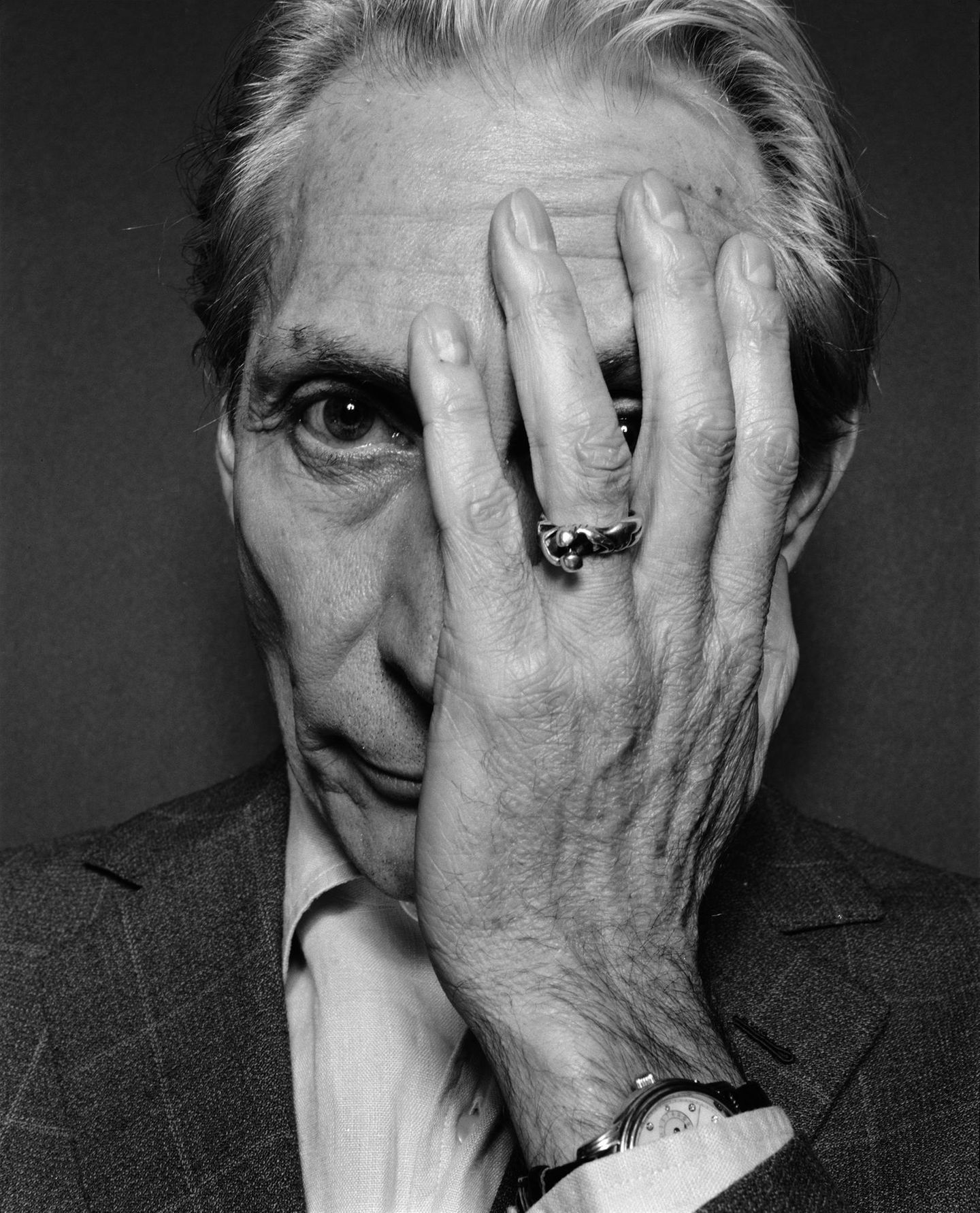 Charlie Watts im Schwarzweiß Portrait mit einer Hand vor dem Gesicht