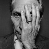 Charlie Watts im Schwarzweiß Portrait mit einer Hand vor dem Gesicht