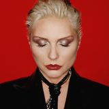 Debbie Harry vor rotem Hintergrund mit strenger Frisur und geschlossenen Augen