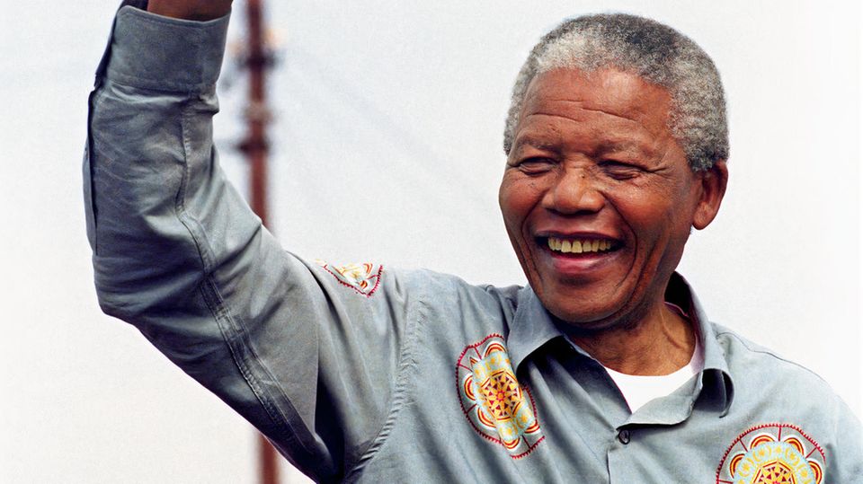Nelson Mandela reckt die Faust in die Luft und lacht