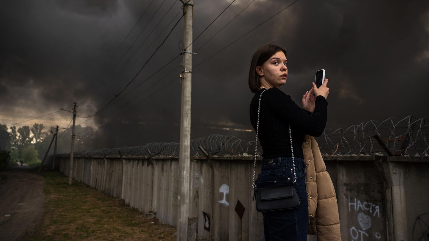 A young woman takes photos of the major fire at the Epicenter shopping center with her cell phone A young woman takes photos of the major fire at the Epicenter shopping center with her cell phone