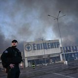 Ein Ukranischer Polizist bewacht ein brennendes Einkaufszentrum