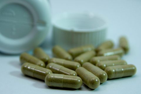 Viele grüne Nahrungsergänzungskapseln liegen auf einer Fläche