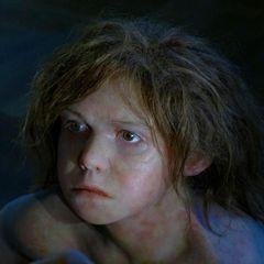 Portrait eines Neandertaler-Jungen mit langen braunen Haaren (Rekonstruktion)