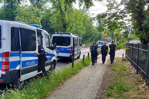 Polizisten gehen am abgesperrten Tatort in der Potsdamer Geschwister-Scholl-Straße entlang