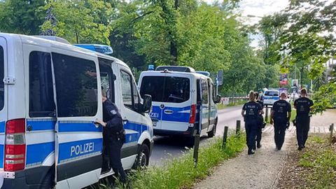 Polizisten gehen am abgesperrten Tatort in der Potsdamer Geschwister-Scholl-Straße entlang