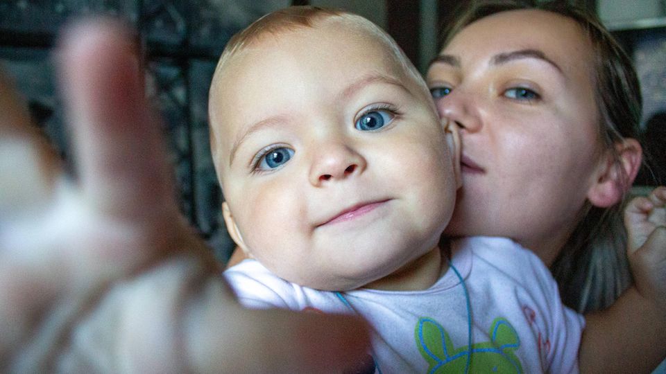 Kinder kriegen: Eine Mutter hält ihr Baby auf dem Arm. Beide schauen in die Kamera