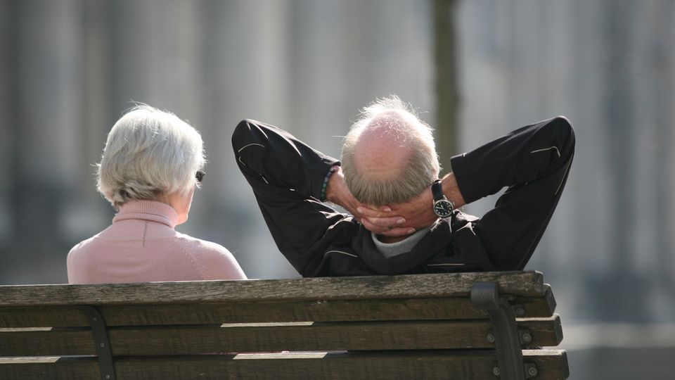 Ein älteres Paar sitzt entspannt auf der Bank in der Sonne (Symbolbild Lebenserwartung)