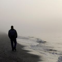 Depression bei Männern: Ein Mann geht einsam am Strand spazieren