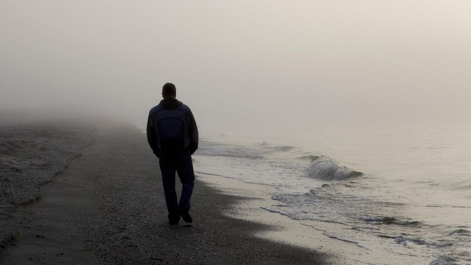 Depression bei Männern: Ein Mann geht einsam am Strand spazieren