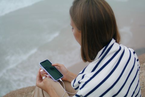 Eine Frau am Strand mit einem Handy. Seit dem Sylt-Skandal versuchen rechtsextreme Musiker die Empörung zu nutzen