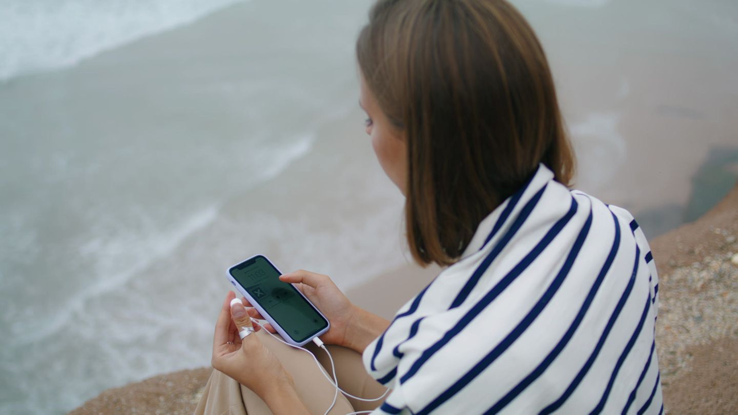 Eine Frau am Strand mit einem Handy. Seit dem Sylt-Skandal versuchen rechtsextreme Musiker die Empörung zu nutzen