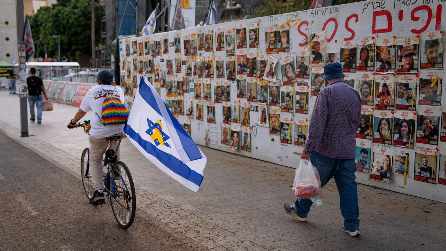 Israel, Tel Aviv: Passanten betrachten die Fotos der im Gazastreifen festgehaltenen Geiseln,