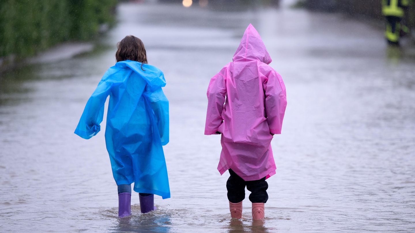 Ein bisschen Spaß muss auch mitten im Ausnahmezustand möglich sein. Die zwei Kinder haben sich passend ausgerüstet und waten über eine geflutete Straße in Dasing im schwäbischen Landkreis Aichach-Friedberg. Noch ist keine Entspannung angesagt, Stakrtregen und Gewitter werden auch am Sonntag über Brandenburg, Thüringen, Sachsen, Bayern und Baden-Württemberg hinwegziehen.