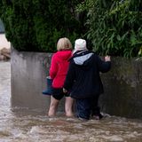In Reichertshofen gehen zwei Frauen eine überflutete Straße entlang. Es hat wie aus Eimern schüttet. Seit Freitagabend dauert der Kampf gegen die Fluten an – und am Sonntag ist noch kein Ende in Sicht. Vielerorts steigen die Pegelstände weiter dramatisch an.