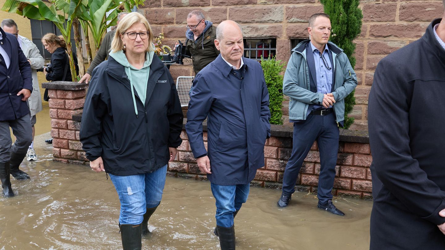 Olaf Scholz geht mit der saarländischen Ministerpräsidentin Anke Rehlinger (SPD) in Gummistiefel durch das Hochwasser