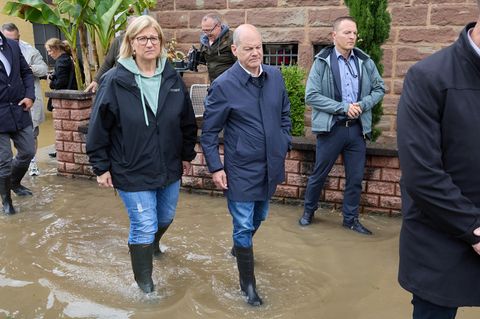 Olaf Scholz geht mit der saarländischen Ministerpräsidentin Anke Rehlinger (SPD) in Gummistiefel durch das Hochwasser