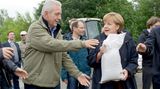 Angela Merkel und Stanislaw Tillich geben einen Sandsack weiter