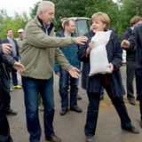 Angela Merkel und Stanislaw Tillich geben einen Sandsack weiter