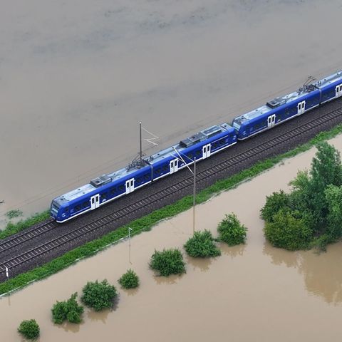 Ein Zug fährt über den höher gelegenen Bahndamm: Das Hochwasser der Schussen überschwemmt Teile von Meckenbeuren in Baden-Württemberg