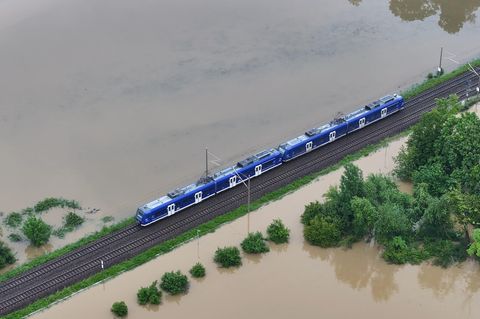 Ein Zug fährt über den höher gelegenen Bahndamm: Das Hochwasser der Schussen überschwemmt Teile von Meckenbeuren in Baden-Württemberg