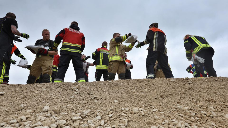 Donauwörth: Feuerwehrleute und freiwillige Helfer stapeln Sandsäcke, um das Hochwasser nach einem Dammbruch zu stoppen