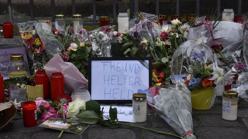 Ein Pappschild mit den Worten "Freund, Helfer, Held" inmitten von Blumen und Kerzen