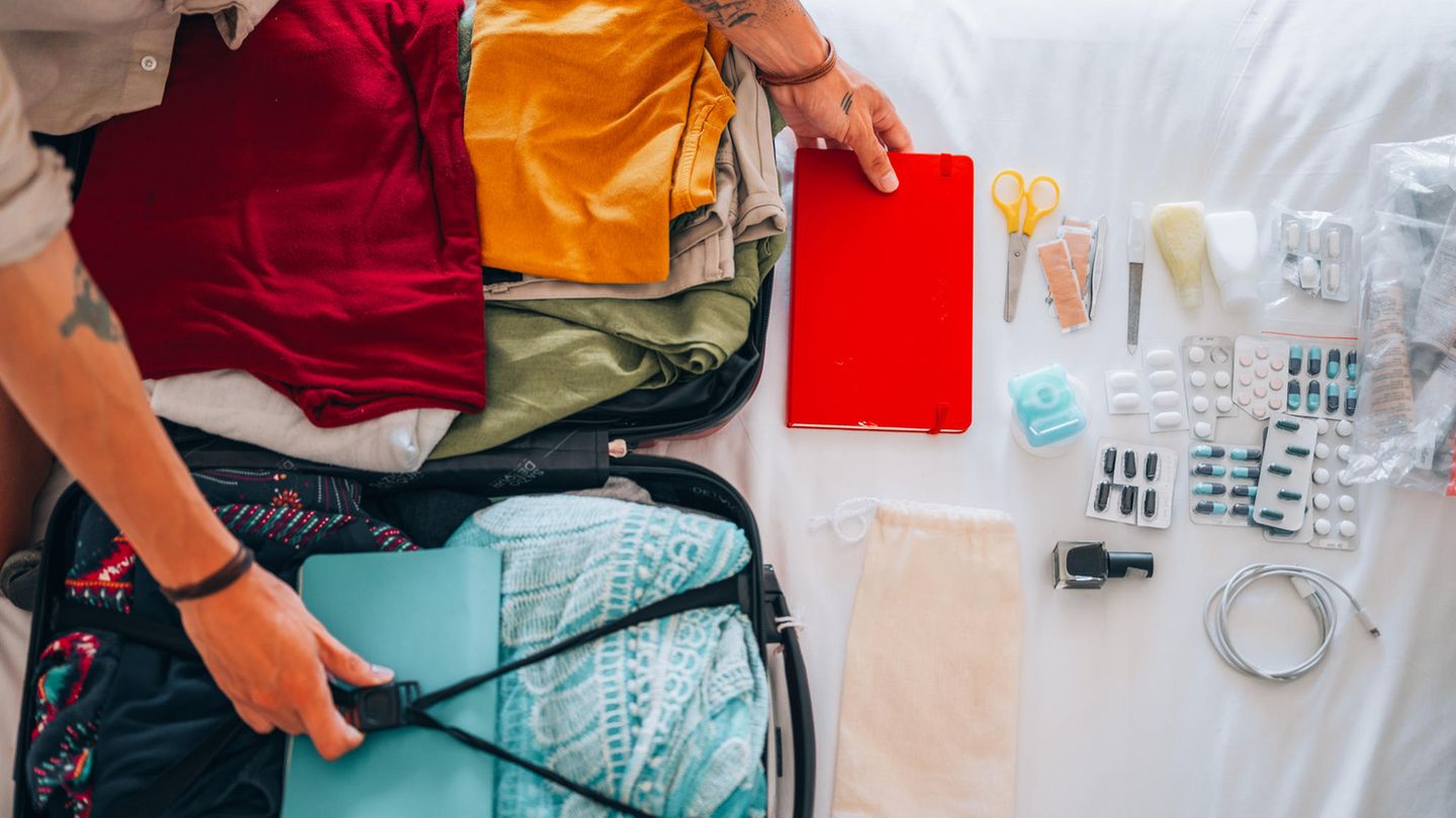 Krank im Urlaub: Aufgeklappter Koffer mit vielen Medikamenten daneben