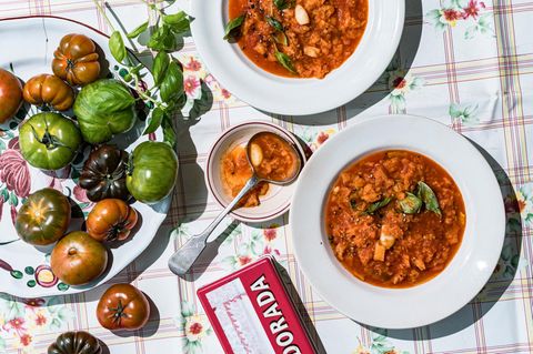 Tomatensuppe angerichtet neben frischen Tomaten
