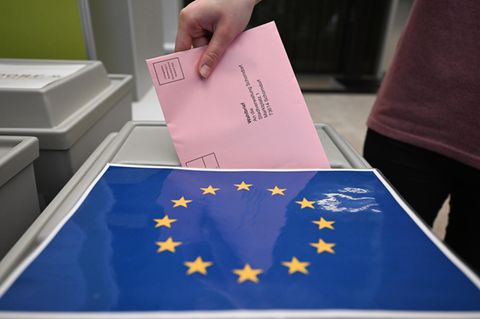 Ein Wahlbrief zur Europawahl wird in eine Urne geschoben