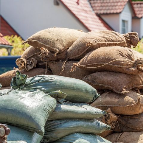 Ein Haufen Sandsäcke liegt vor Häusern im Überschwemmungsgebiet in Süddeutschland