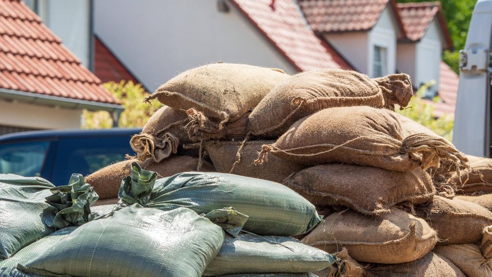 Ein Haufen Sandsäcke liegt vor Häusern im Überschwemmungsgebiet in Süddeutschland