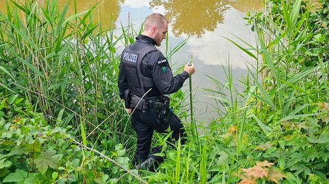 Ein Polizist sucht an einem Gewässer in Döbeln in Sachsen nach einem neunjährigen Mädchen, das als vermisst gemeldet wurde