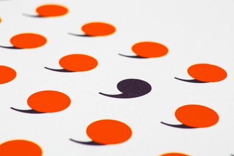 Hellrote Kommata und ein schwarzes Komma auf einem Blatt Papier