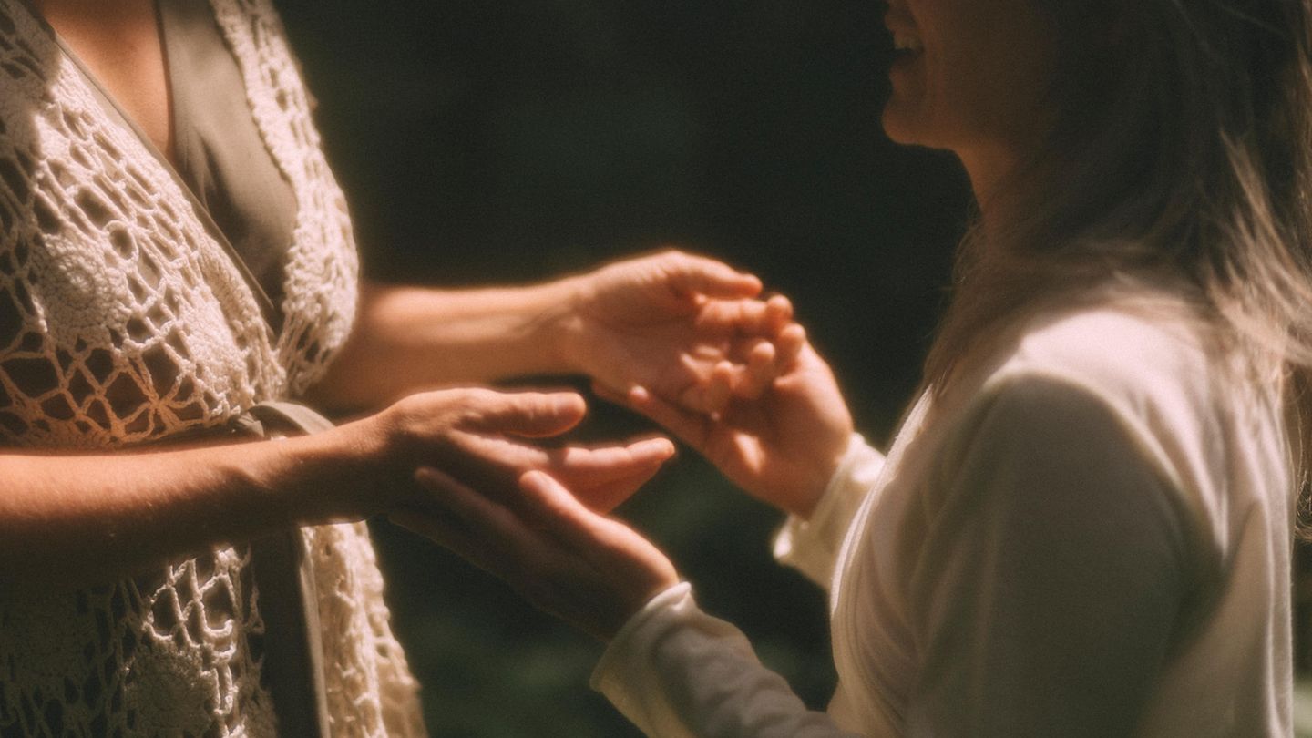 Zwei Frauen halten sich an den Händen