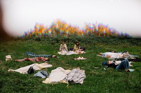 Frauen liegen auf einer Wiese in einem Kreis und machen eine geführte Meditation