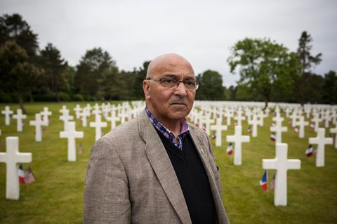 Priester Daniel Lefrançois vor Reihen weißer Kreuze auf einem Soldatenfriedhof in der Normandie
