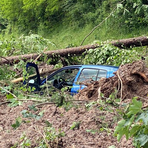 Ein blaues Auto steckt nach dem Hochwasser und einem Erdrutsch im Matsch fest