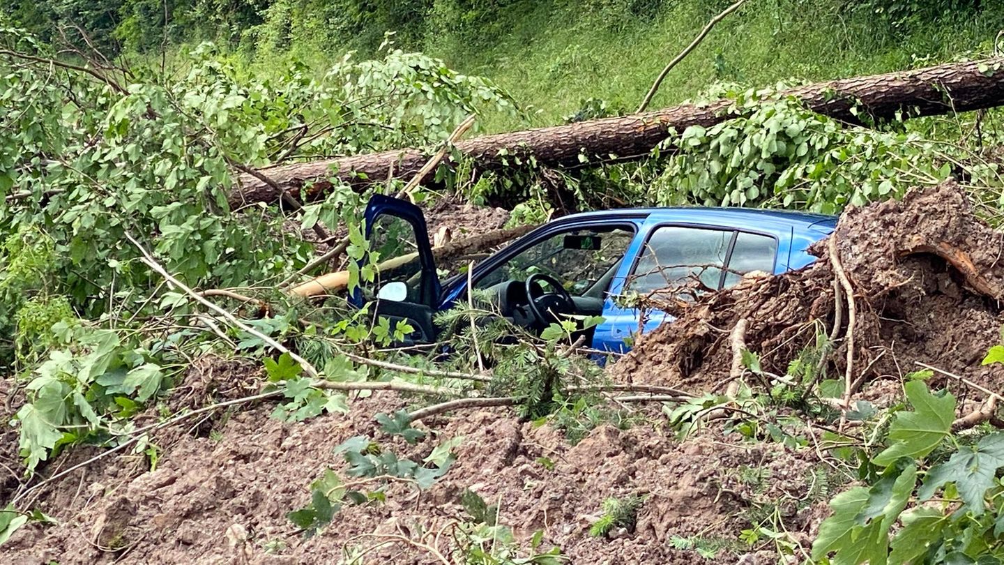 Ein blaues Auto steckt nach dem Hochwasser und einem Erdrutsch im Matsch fest