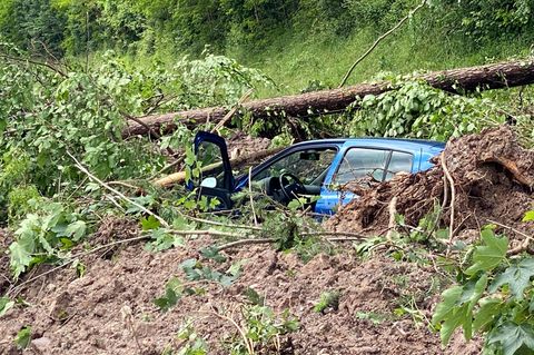 Ein blaues Auto steckt nach dem Hochwasser und einem Erdrutsch im Matsch fest