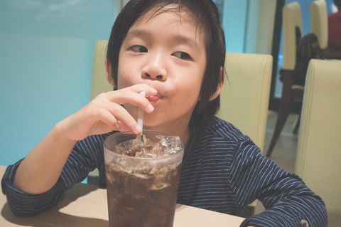 Thema Süßstoffe: Kind trinkt Cola aus einem Glas