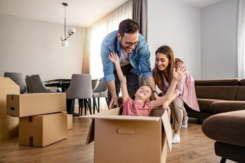 Wohnungsnot: Eine junge Familie freut sich inmitten von Umzugskartons über eine neue Wohnung