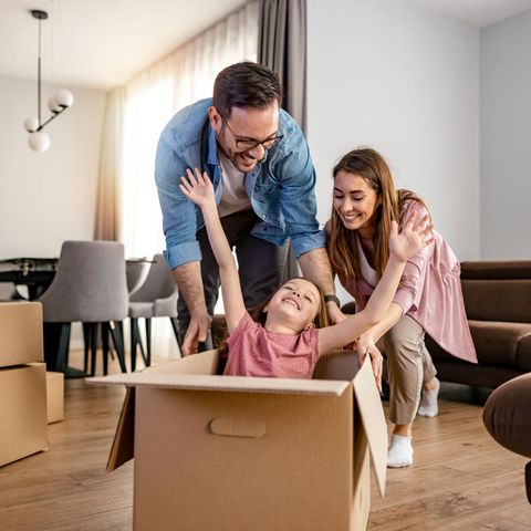 Wohnungsnot: Eine junge Familie freut sich inmitten von Umzugskartons über eine neue Wohnung