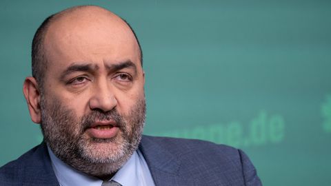 Porträt des Grünen-Co-Vorsitzenden Omid Nouripour vor Stellwand mit grünem Parteilogo