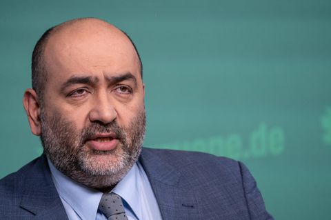 Porträt des Grünen-Co-Vorsitzenden Omid Nouripour vor Stellwand mit grünem Parteilogo