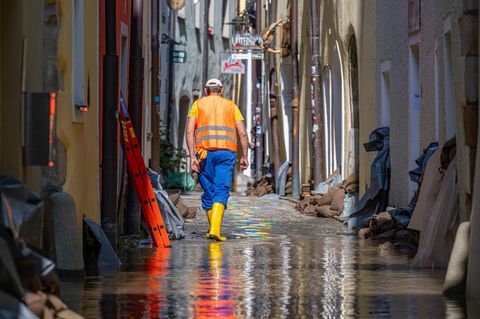 Ein Helfer geht, nachdem das Hochwasser der Donau zurückgegangen ist, durch eine Gasse mit Sandsäcken