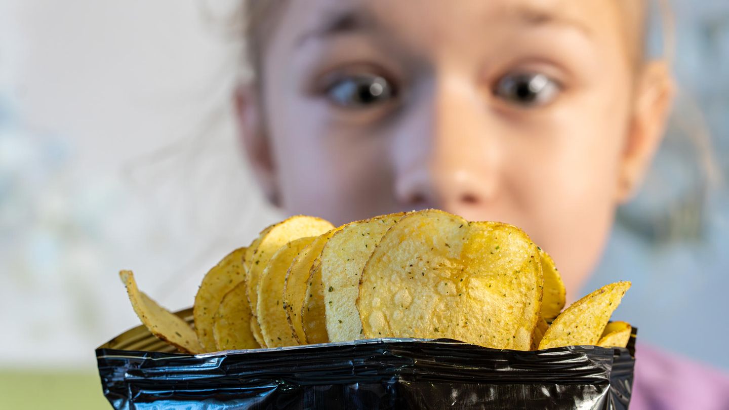 Mädchen schaut auf eine Chipstüte
